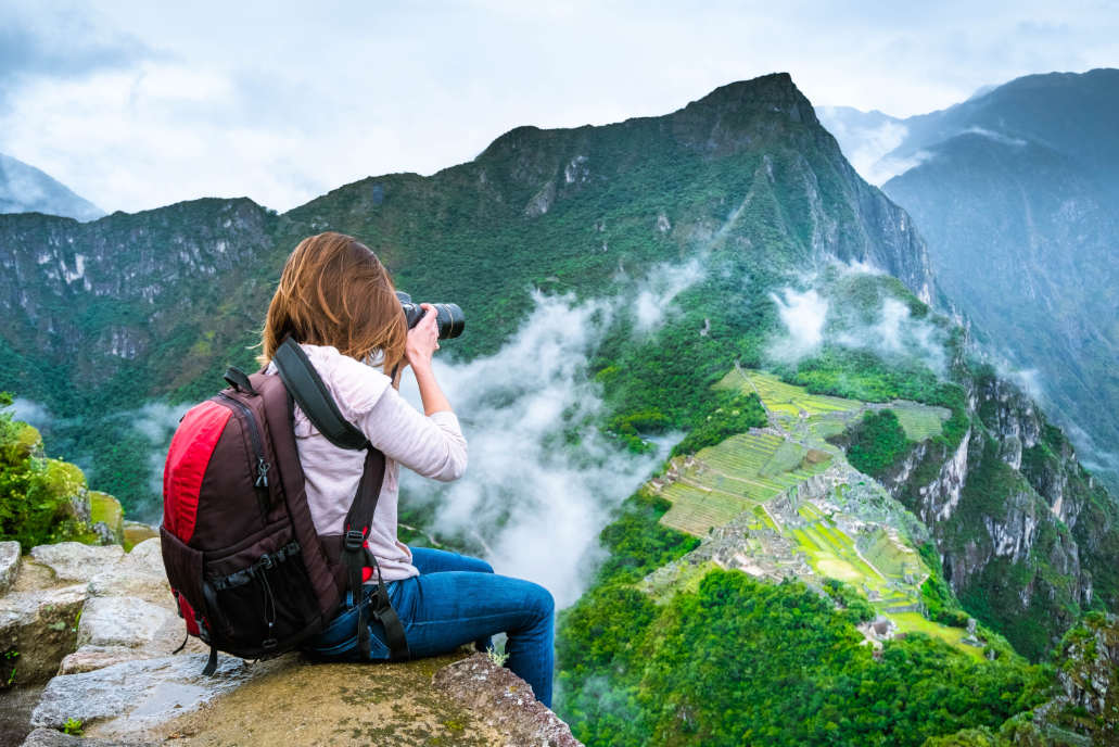 Turista sacando fotos desde la cima del Huayna Picchu